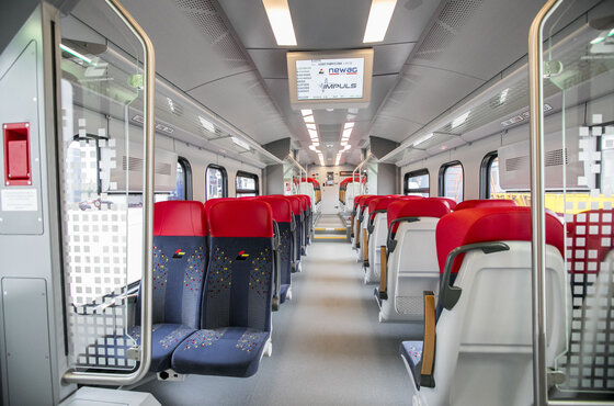 Interior of an Impuls II train: red and navy seat rows along the central aisle